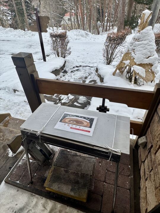 テラスから続く雪道と、木立が広がる雪景色